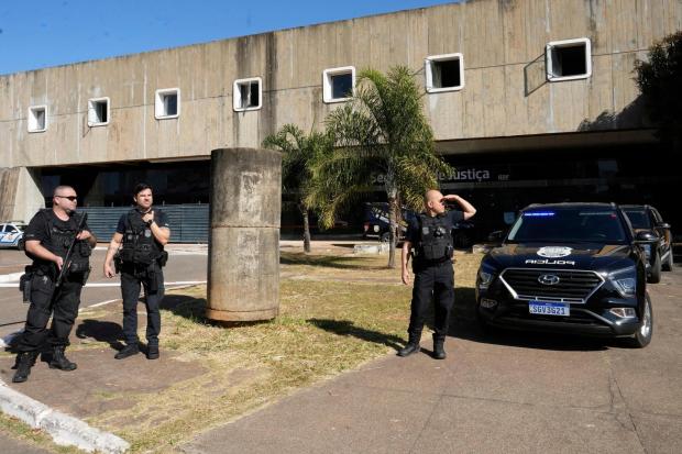 Federal police stand outside the Secretariat of Penitentiary Administration office where Brazil's former President Jair Bolsonaro arrived after the Supreme Court ordered him to be fitted with an electronic ankle monitor, in Brasilia, Brazil, Friday, July 18, 2025. (AP Photo/Eraldo Peres)