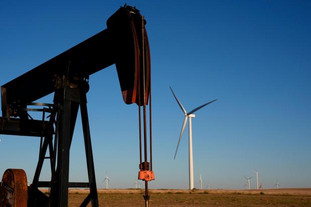 FILE - Pumpjacks operate in the foreground while a wind turbines at the Buckeye Wind Energy wind farm rise in the distance Monday, Sept. 30, 2024, near Hays, Kan. (AP Photo/Charlie Riedel, File)