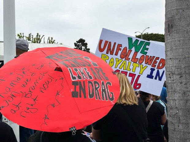 A sign made out of an umbrella along with a second handmade sign are among the clever signs seen at the No Kings protest at Bixby Annex Park in Long Beach, June 14, 2025. (Photo by Stephanie E'amato, Contributing Photographer)