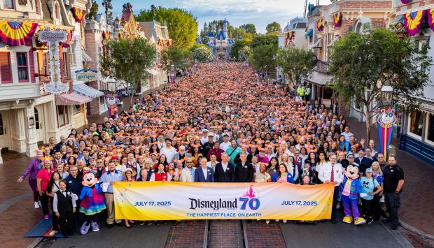 Disneyland Resort President Thomas Mazloum (left), Disney CEO Bob Iger (center) and Disney Parks boss Josh D'Amaro (right) pose for a group photo on Main Street U.S.A. with Disneyland employees on July 17, 2025 in celebration of the park's 70th anniversary. (Courtesy of Disneyland)