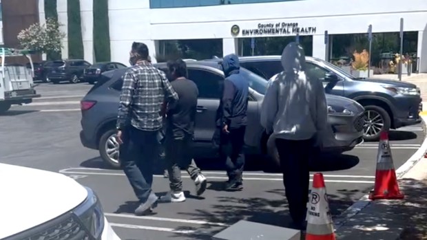 Masked plainclothes federal agents detain a man in a parking lot shared with the Santa Ana courthouse. (Photo by Mona Darwish)