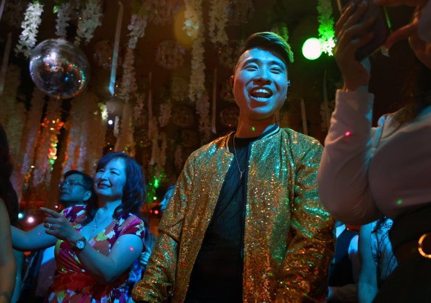 Duy Nguyen-Amigo, middle, smiles and laughs with his friends on the dance floor after singing on stage at his parents' banquet hall, Mon Amour, in the city of Anaheim. (Photo by Karen Tapia, Contributing Photographer)