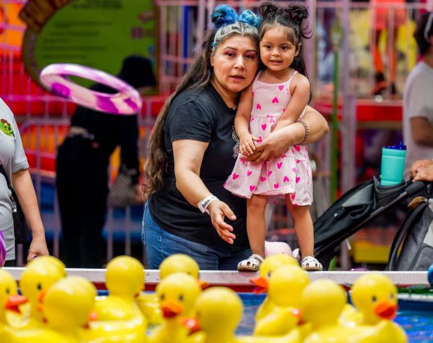 Alejandra Ramos and her daughter Shoshanna, 2, try their luck at tossing at the rubber duck carnival game in hopes of winning a prize during a nighttime visit to the OC Fair at the OC Fair & Event Center in Costa Mesa on Sunday, July 30, 2023. (Photo by Leonard Ortiz, Orange County Register/SCNG)