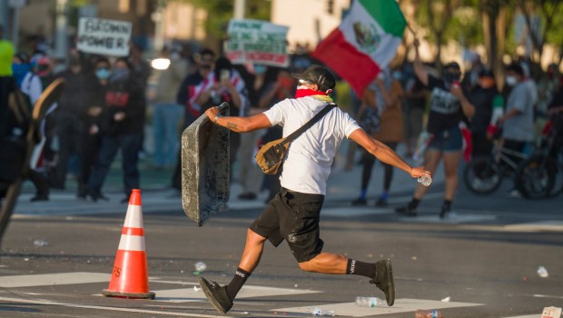 A man uses a plastic tub to shield himself from pepper gun projectiles as he prepares to throw a water bottle at federal police during protests against ICE outside the Federal Building in downtown in Santa Ana on Monday, June 9, 2025. (Photo by Leonard Ortiz, Orange County Register/SCNG)