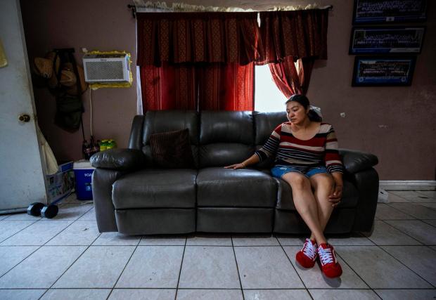 Maria Murillo, wife of ICE detainee Jose Luis Zavala places her hand on the couch where she would sit with her husband Jose after he would get home from a long day working and return home to be with his family in Pomona, on Thursday, July 17, 2025. (Photo by Terry Pierson, The Press-Enterprise/SCNG)