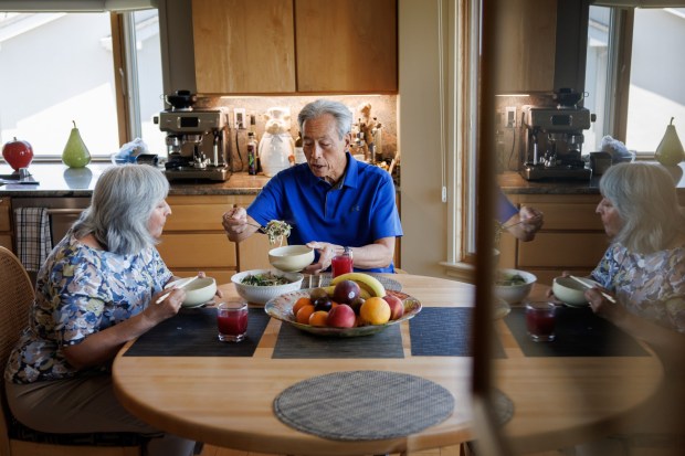 Randy Tom, center, and his wife, Vera Tom, eat lunchbowls of stir-fried pork, bok choy, and bean sproutsat their Redwood City home on June 27, 2025. (Dai Sugano/Bay Area News Group)