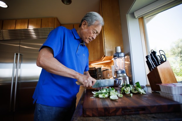 Randy Tom cuts bok choy as he prepares lunch at his Redwood City home on June 27, 2025. (Dai Sugano/Bay Area News Group)