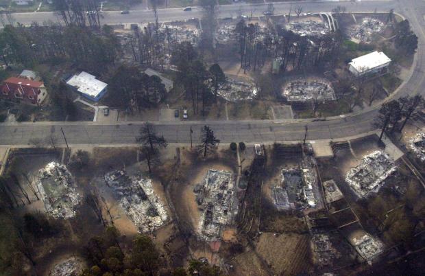 FILE - Houses that have burned to the ground by the Cerro Grande fire sit along a street in north Los Alamos, N.M., May 12, 2000. (AP Photo/Jake Schoellkopf, File)